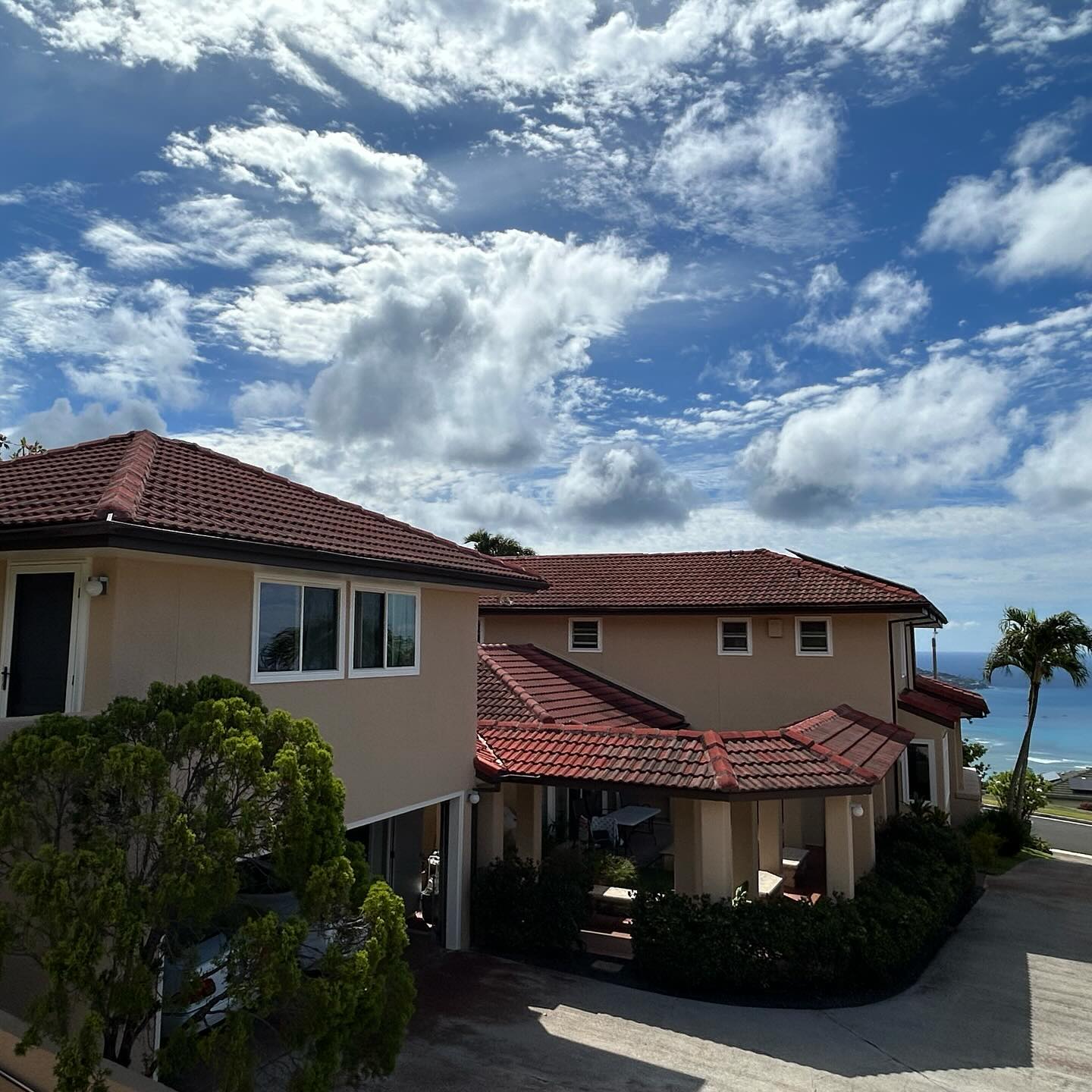 Hillside Oahu home repainted in warm sand stucco with red tile roof and ocean view