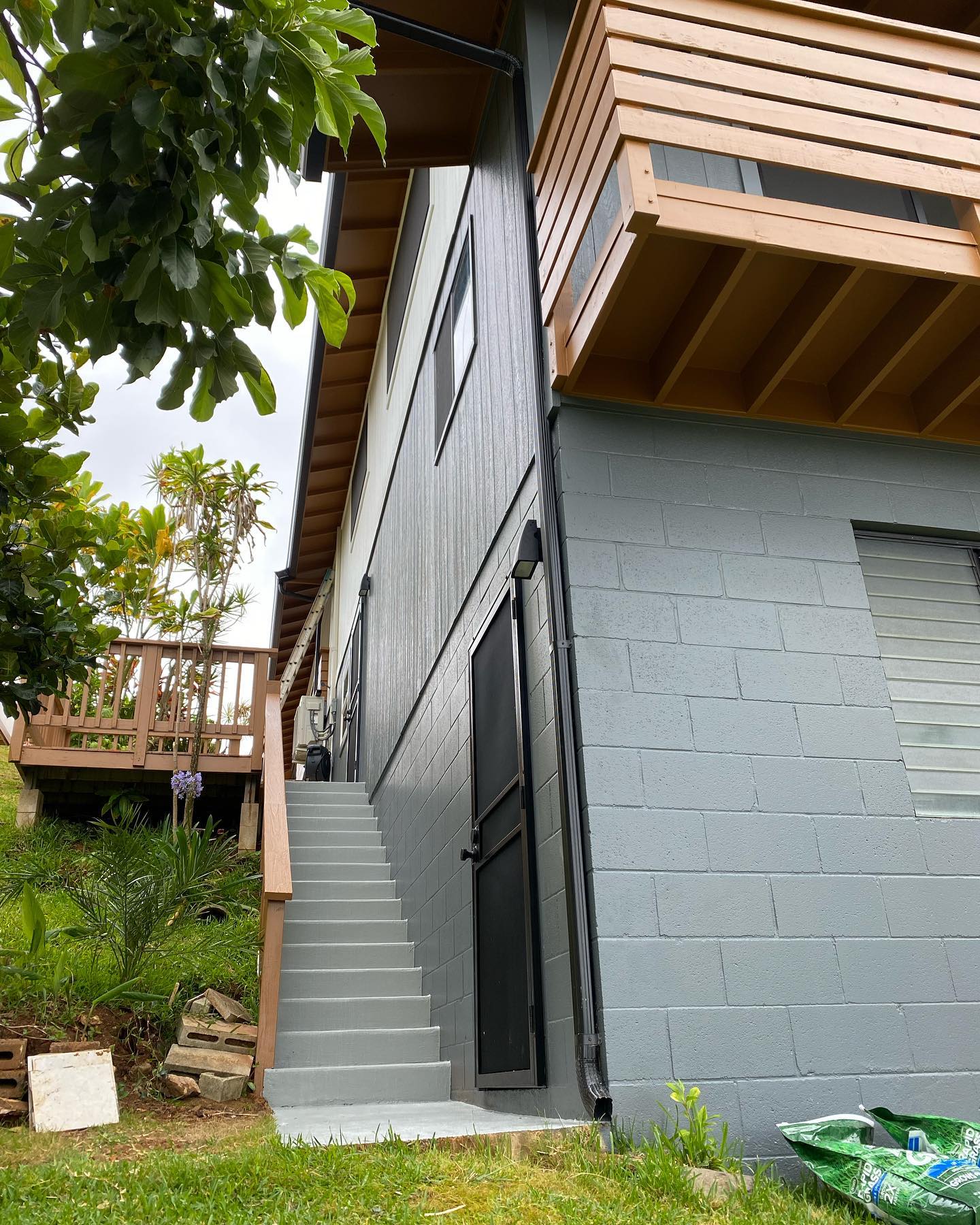 Grey CMU foundation and board and batten siding repaint with redwood deck above on Oahu